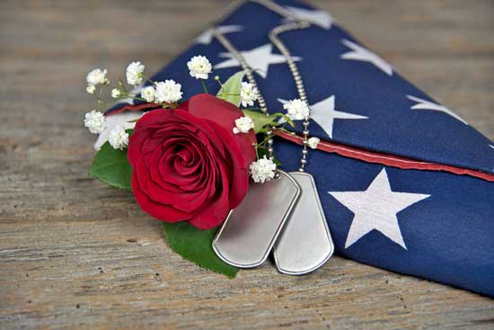Red rose on folded flag with dog tags